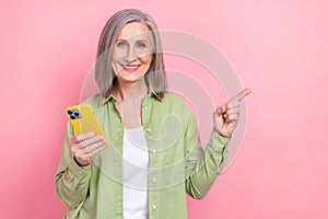 Photo of woman gray hair pensioner hold new gadget iphone indicating empty space finger true information isolated on