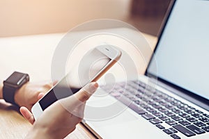 Photo of a woman holding a blank screen phone and a computer. and put a smart watch, film effect.