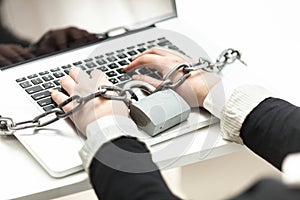 Photo of woman locked in chain typing on laptop