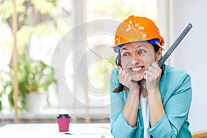 Photo of woman in orange helmet holding a ruler.