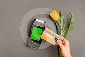 photo of woman paying with credit card by paypass near yellow tulip