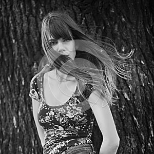 Photo of woman posing near a tree with windy hair