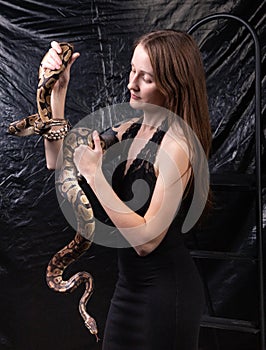 Photo of woman with snakes in hands on dark background