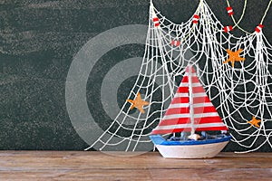 Photo of wooden sailing boat in front of chalkboard with nautical illustrations.