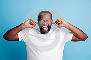 Photo of woried annoyed man fingers cover ears wear white t-shirt over blue background