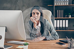 Photo of worried horrified girl sit desk work remote computer bite finger nails feel fear about company crisis bankrupt