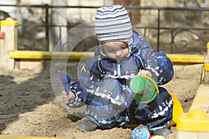 A 2-year- old boy playing in a sandbox