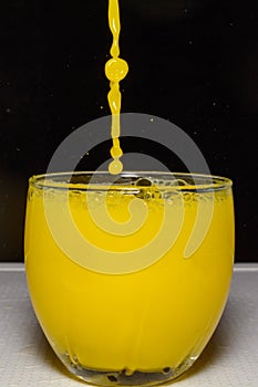 Photo of yellow water trickle and drops on black background