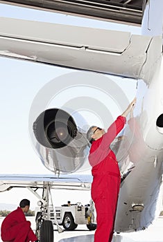 Portrait of young aeronautic engineer checking airplane propeller photo