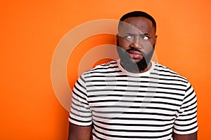 Photo of young african man moody displeased discontent look empty space isolated over orange color background