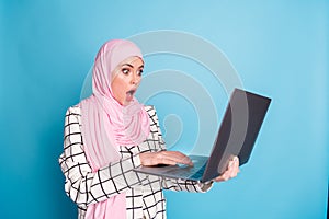 Photo of young amazed shocked muslim woman read news email trouble mistake wear hijab isolated over blue color