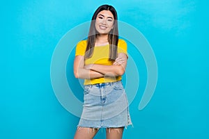 Photo of young asian beauty girl hold crossed arms toothy smile wear denim skirt yellow t-shirt isolated blue color