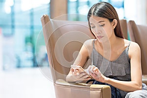 Photo of young asian woman`s hand holding smart phone typing on device lying on sofa at home