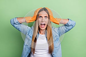 Photo of young astonished woman arms touch head stupor panic dirty mess isolated over green color background