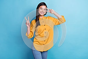 Photo of young attractive asian girl happy positive smile show peace victory v-sign isolated over blue color background