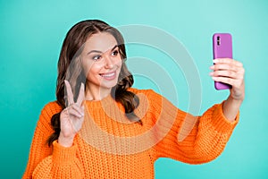 Photo of young attractive beautiful happy cheerful smiling girl show v-sign take selfie on phone isolated on teal color
