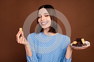 Photo of young attractive girl happy positive smile eat dessert tasty candy sugar calories isolated over brown color