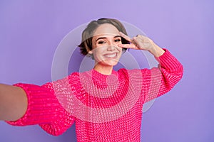 Photo of young attractive girl happy positive smile playful show peace cool v-sign make selfie isolated over violet