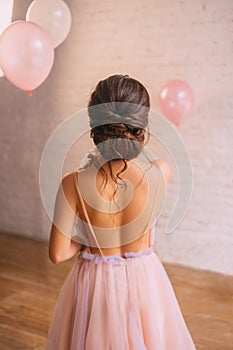 Photo of a young attractive maiden with amazing skin behind, the girl is dressed in a light delicate peach dress with
