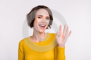 Photo of young attractive woman happy positive smile waving hand hello hi greetings isolated over grey color background