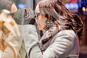 Portrait of young attractive woman looking at the dress on a manequin in shop through the window photo