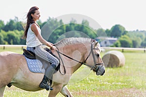 Portrait of young attractive woman riding horse in ranch