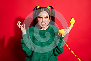 Photo of young beautiful angry furious girl hold yellow telephone after argument isolated on red color background