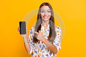 Photo of young beautiful girl happy smile point indicate finger cellphone advert promotion choose isolated over yellow