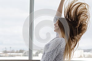 Photo of young beautiful happy smiling woman with long hair near the window. photo