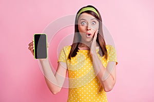 Photo of young beautiful shocked amazed surprised girl hold hand cheekbone demonstrate phone isolated on pink color photo