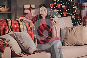 Photo of young beautiful smiling attractive joyful positive good mood woman sit sofa using smartphone new year eve at