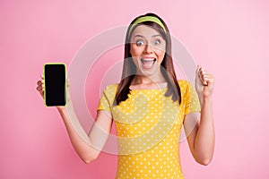 Photo of young beautiful smiling cheerful excited crazy girl raise fist in victory hold phone isolated on pink color