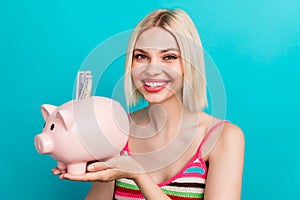 Photo of young blonde girl holding piggy bank collect more money for shopping season advert ad isolated on aquamarine