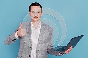 Photo of young business man happy positive smile show thumb-up like recommend laptop isolated over blue color background