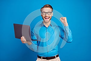 Photo of young business man happy positive smile use laptop rejoice victory fists hand isolated over blue color