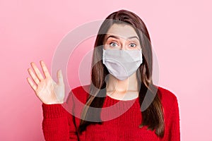 Photo of young charming woman wave hand look camera wear mask red pullover isolated pink color background