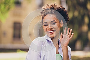 Photo of young cheerful african woman happy positive smile waving hand hello hi greeting glad nature urban outdoors