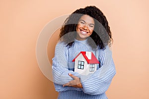 Photo of young cheerful girl hug cuddle house relocation property isolated over beige color background