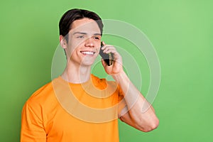 Photo of young cheerful happy dreamy man look empty space talk phone smile isolated on green color background