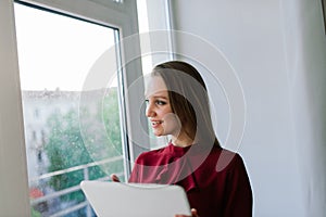 Photo of young cheerful happy woman indoors at home using laptop computer talking by mobile phone