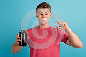 Photo of young cheerful man advertise hold meds drugs suggest recommend isolated over blue color background