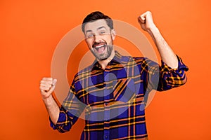 Photo of young cheerful man happy positive smile celebrate win victory lucky lottery fists hands isolated over orange