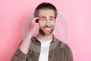 Photo of young cheerful man happy positive smile finger touch head think forget memory isolated over pink color