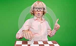 Photo of young cheerful positive young boy idea genius move horse chess isolated on green color background