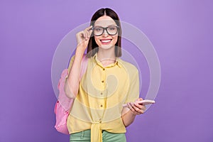 Photo of young cheerful school girl eyewear use mobile chating typing sms isolated over violet color background