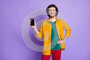 Photo of young cheerful smiling happy man male guy show demonstrate touchscreen smartphone mobile isolated on purple