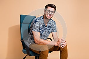 Photo of young cheerful team leader sitting boss armchair waiting for interview with new candidates isolated on beige