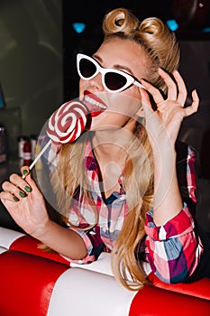 Photo of young cheerful woman liking lollipop and smiling