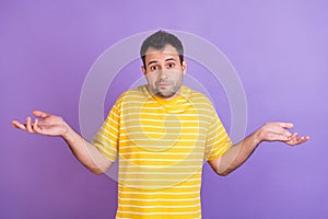 Photo of young clueless ignorant man shrug shoulders no idea puzzled isolated on purple color background