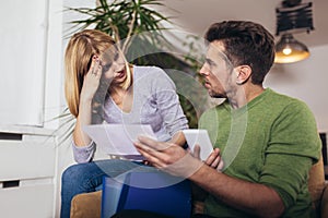 Young couple embracing and calculating the bills at home
